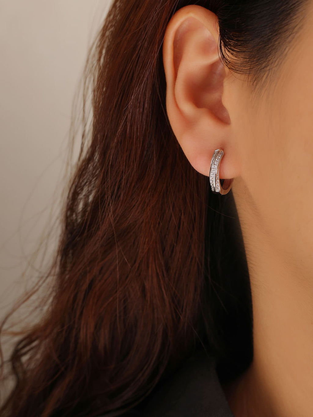 Crossed-band cubic zirconia hoop earrings in hallmarked, rhodium-plated 925 sterling silver – worn view – DRESCHER Jewellery®