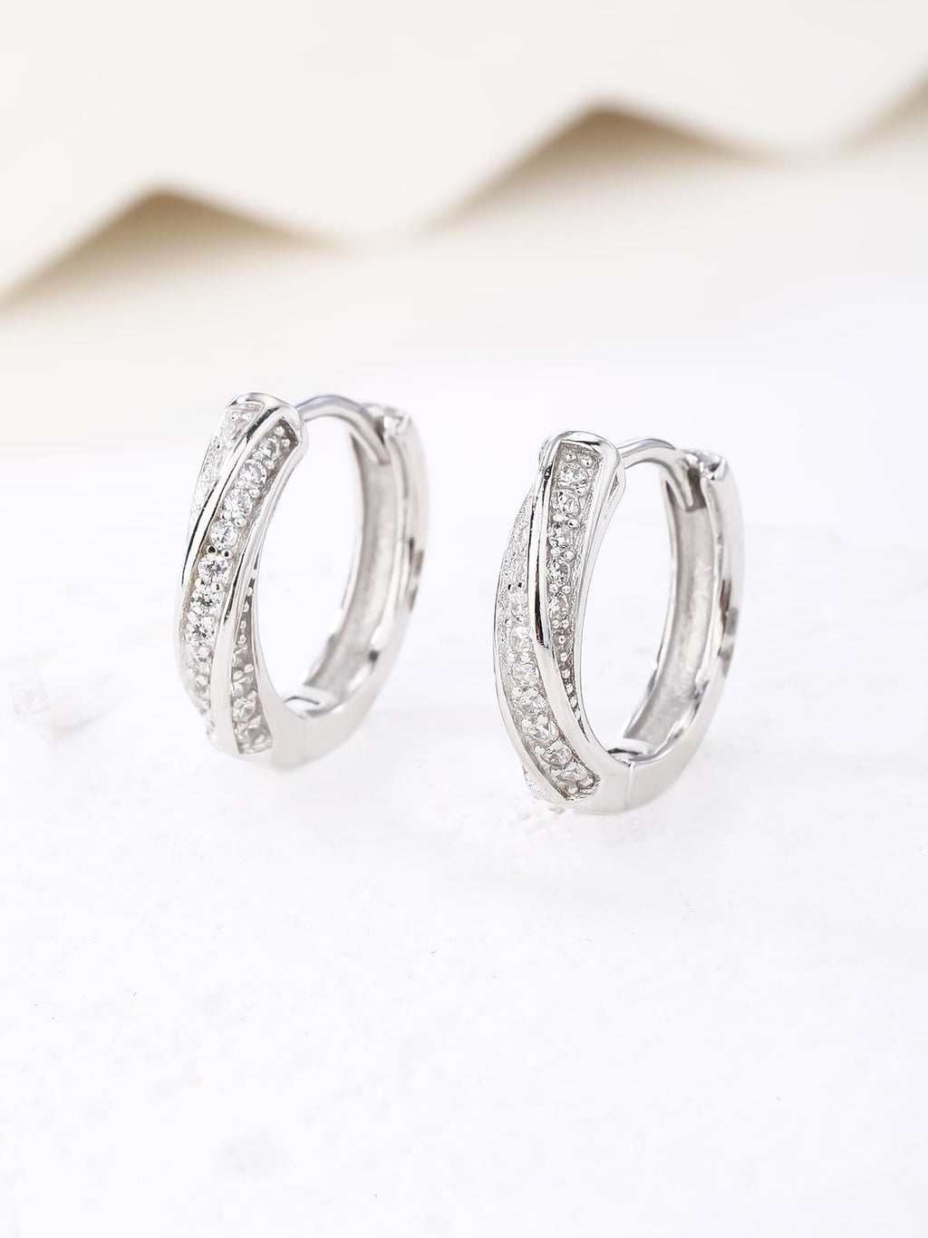 Crossed-band cubic zirconia hoop earrings in hallmarked, rhodium-plated 925 sterling silver – display view – DRESCHER Jewellery®