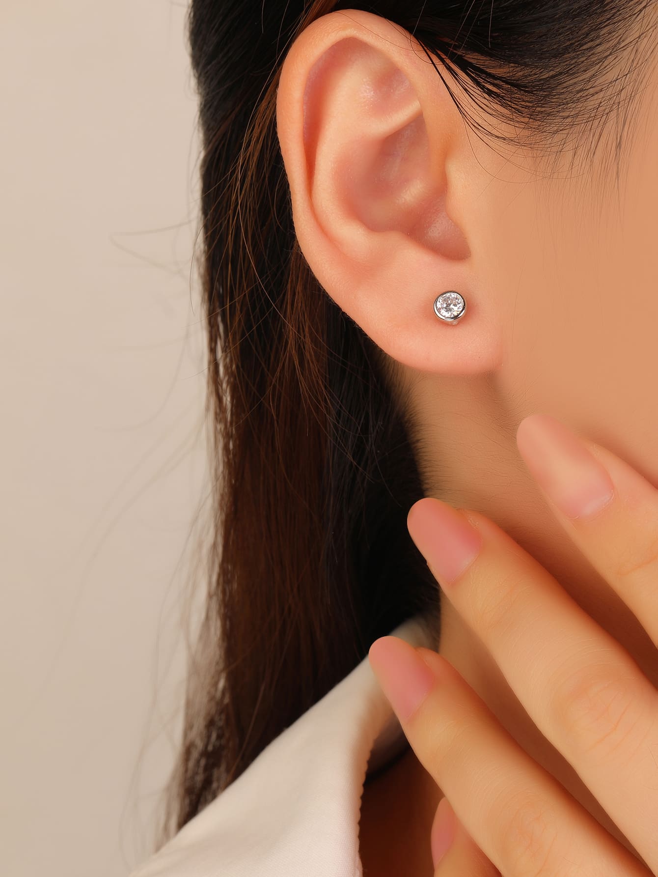 White cubic zirconia bezel-set stud earrings in hallmarked, rhodium-plated 925 sterling silver – worn view – DRESCHER Jewellery®