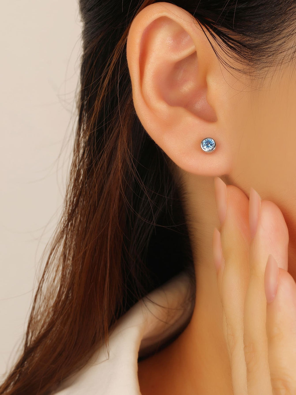 Blue cubic zirconia bezel-set stud earrings in hallmarked, rhodium-plated 925 sterling silver – worn view – DRESCHER Jewellery®