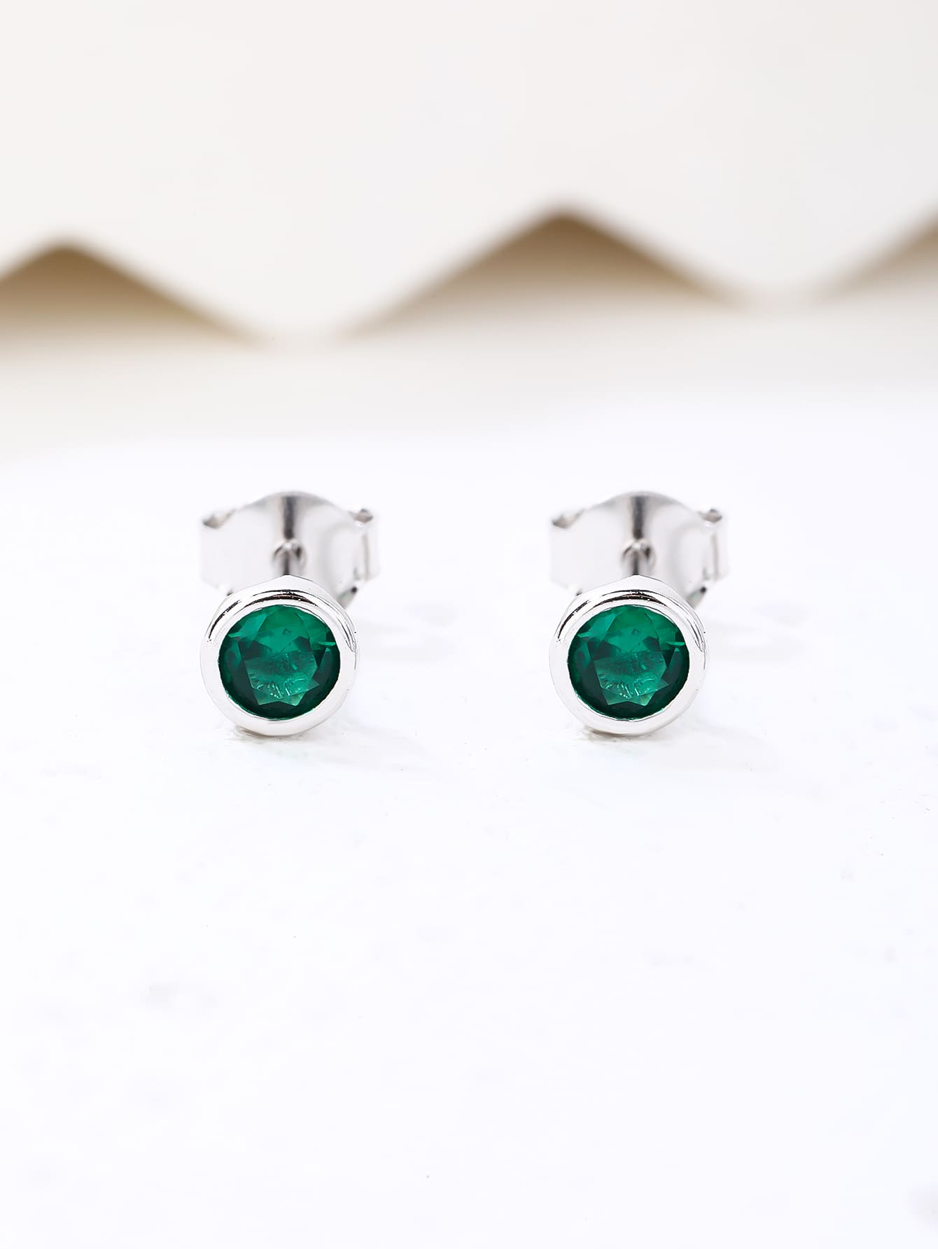 Green cubic zirconia button-set stud earrings in hallmarked, rhodium-plated 925 sterling silver – lifestyle view – DRESCHER Jewellery®