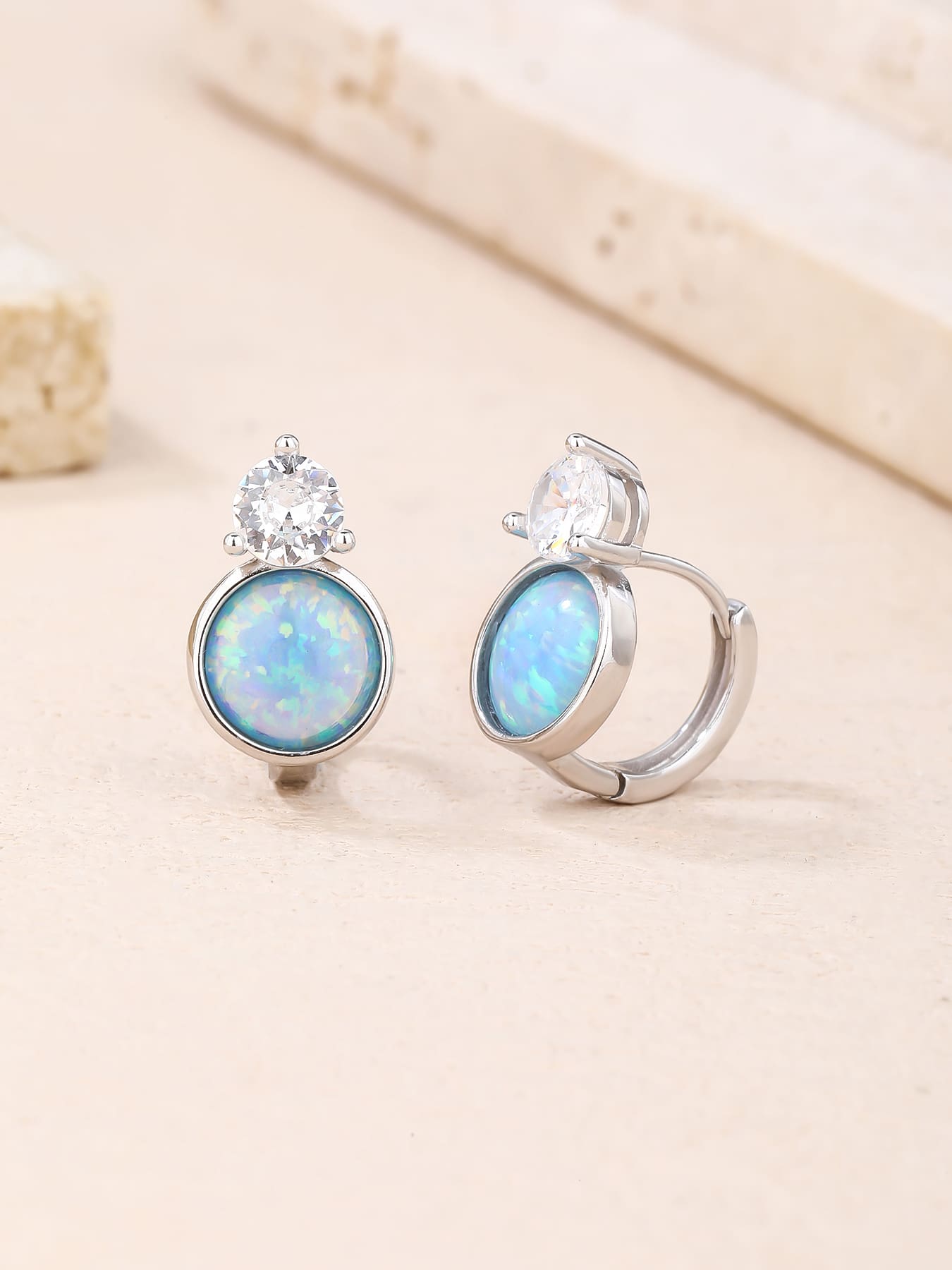 Light blue opal and white cubic zirconia huggie earrings in hallmarked, rhodium-plated 925 sterling silver – lifestyle view – DRESCHER Jewellery®