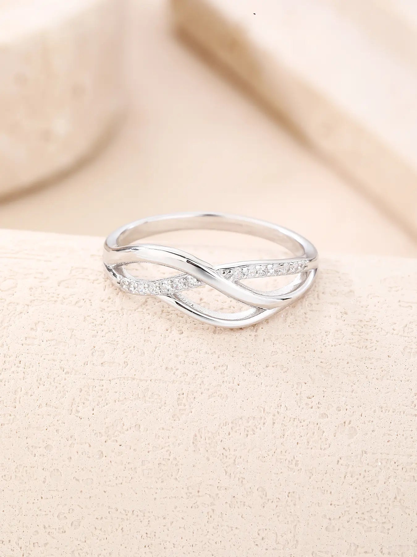 Silver ring with curved motif and white stones