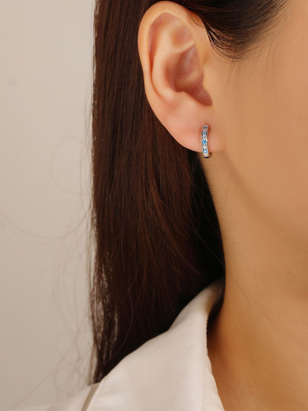 Blue and white cubic zirconia hoop earrings in hallmarked, rhodium-plated 925 sterling silver – worn view – DRESCHER Jewellery®