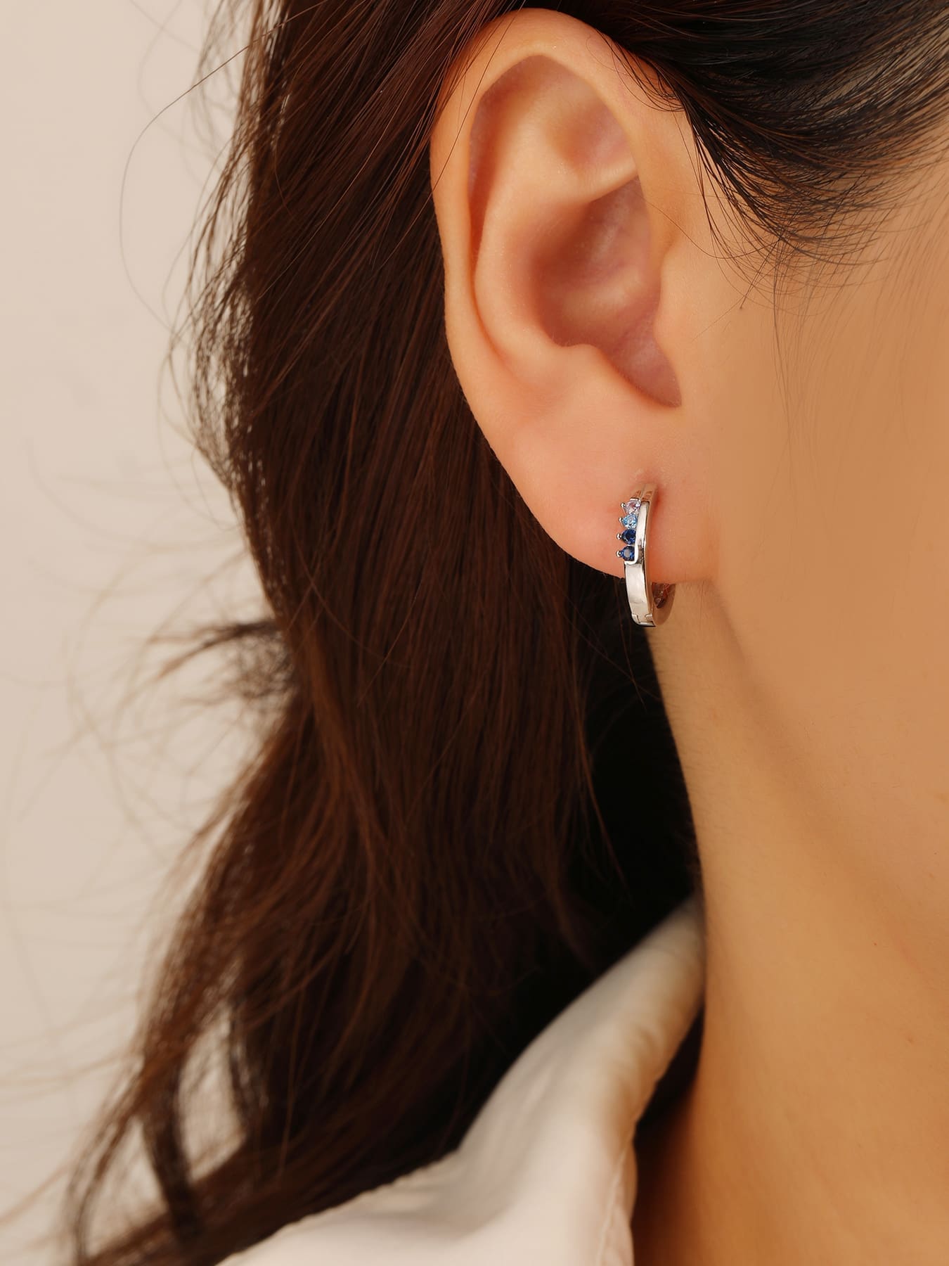 Blue, light blue and white cubic zirconia hoop earrings in hallmarked, rhodium-plated 925 sterling silver – worn view – DRESCHER Jewellery®