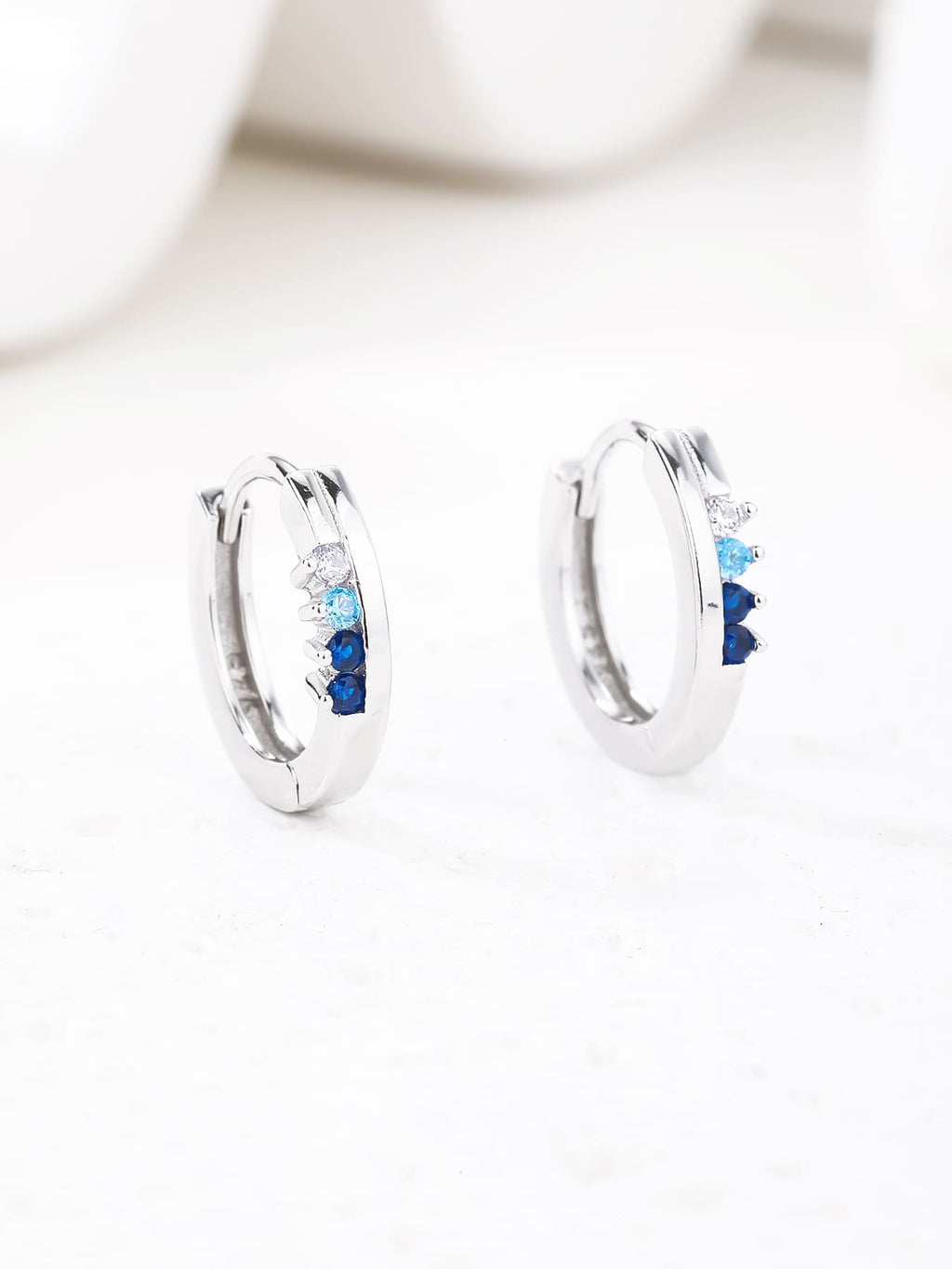 Blue, light blue and white cubic zirconia hoop earrings in hallmarked, rhodium-plated 925 sterling silver – display view – DRESCHER Jewellery®
