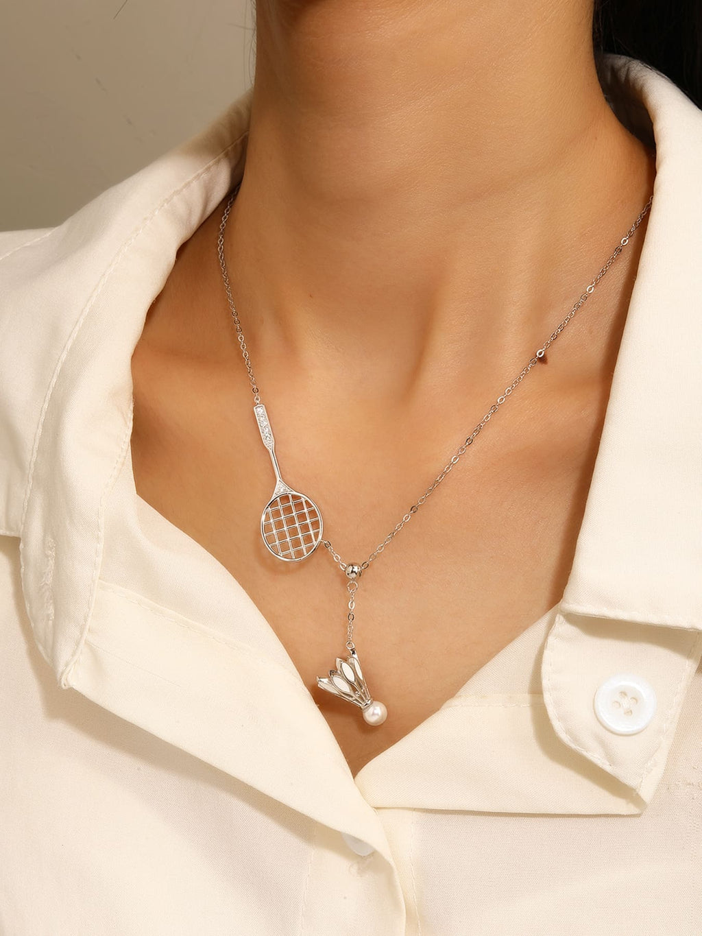 Badminton racket and shuttlecock pendant necklace with white cubic zirconia and pearl detail, crafted with hallmarked, rhodium-plated 925 sterling silver – worn view – DRESCHER Jewellery®