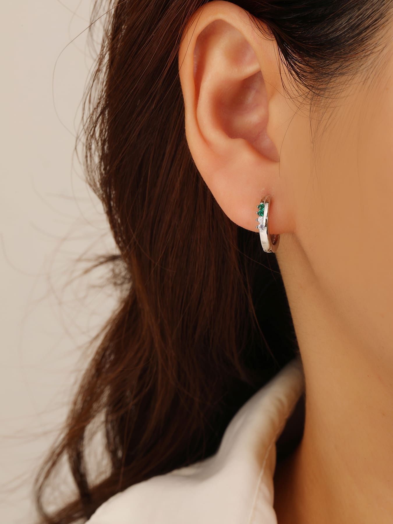 Green and white cubic zirconia hoop earrings in hallmarked, rhodium-plated 925 sterling silver – worn view – DRESCHER Jewellery®